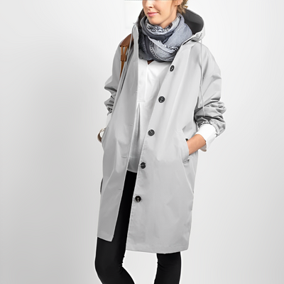 Femme portant un manteau imperméable gris avec capuche, écharpe bleue, chemise blanche et pantalon noir, style mode automne-hiver.