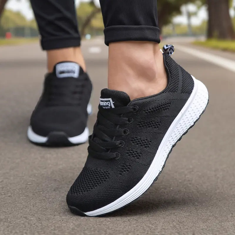 Chaussures de sport noires pour homme sur route, semelle blanche, design respirant, idéales pour course à pied et fitness en extérieur.