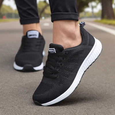 Chaussures de sport noires pour homme sur route, semelle blanche, design respirant, idéales pour course à pied et fitness en extérieur.