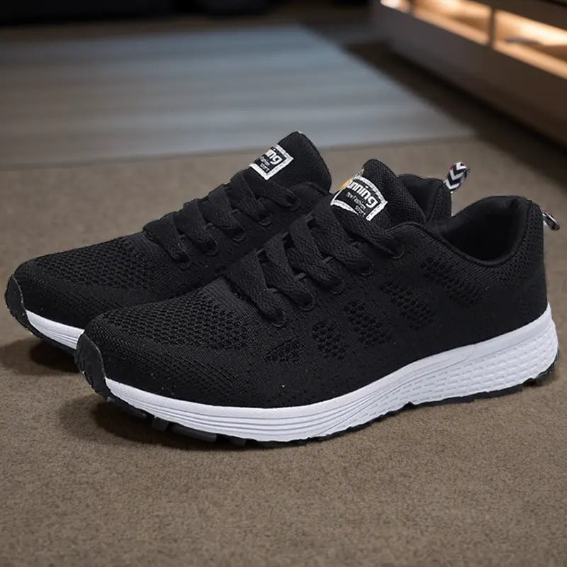 Chaussures de sport noires en maille respirante avec semelle blanche, idéales pour la course à pied. Design moderne et confortable pour hommes.