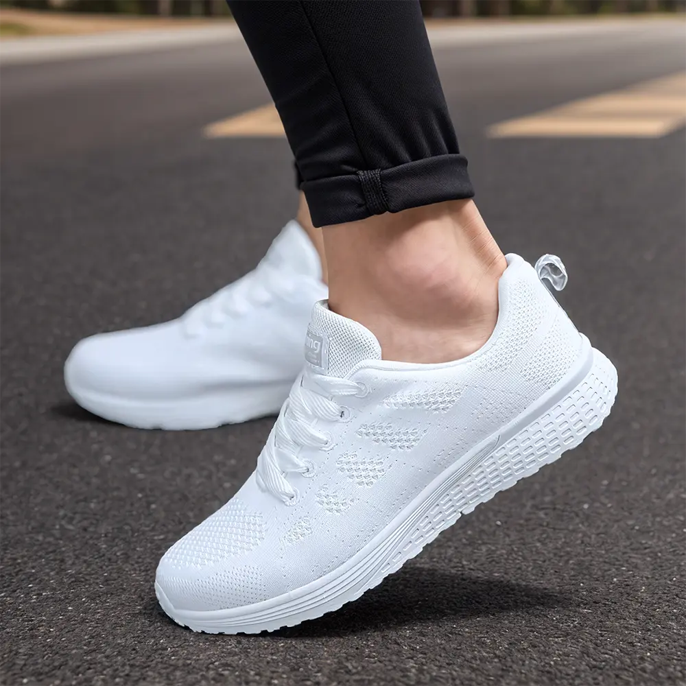 Chaussures de sport blanches pour homme, légères et respirantes, portées sur route asphaltée. Idéales pour la course et le fitness.