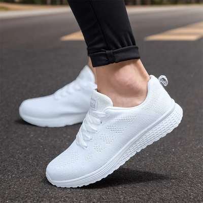 Chaussures de sport blanches pour homme, légères et respirantes, portées sur route asphaltée. Idéales pour la course et le fitness.