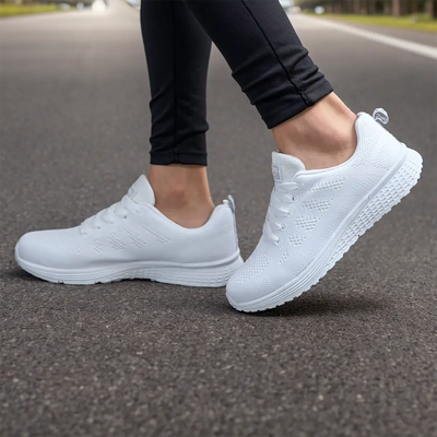 Baskets blanches modernes sur route, portées par une personne en leggings noirs. Chaussures de sport confortables pour course et marche.