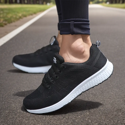 Chaussures de course noires sur route, semelle blanche, portées par une personne en leggings. Idéal pour fitness, jogging, sport en plein air.