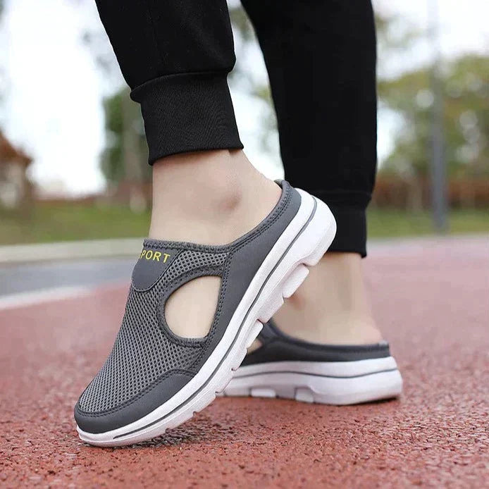 Chaussures de sport grises pour homme, design respirant, semelle blanche, portées sur une piste rouge. Confort et style pour la marche.
