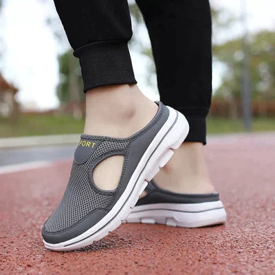 Chaussures de sport grises pour homme, design respirant, semelle blanche, portées sur une piste rouge. Confort et style pour la marche.