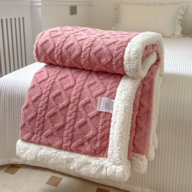 Couverture rose en peluche avec motif géométrique, bordure blanche en fausse fourrure, posée sur un lit blanc. Accessoire de décoration intérieure cosy.