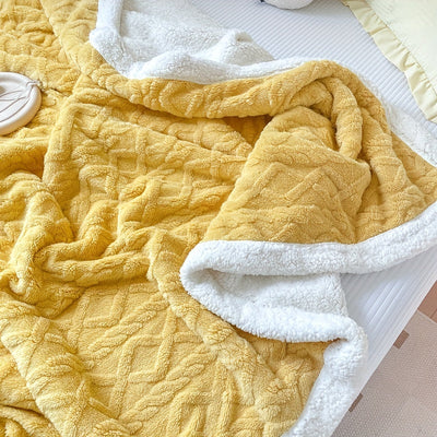 Couverture en polaire jaune et blanche sur un lit, texture douce et moelleuse, idéale pour la décoration de chambre et le confort hivernal.
