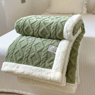 Couverture en laine verte texturée avec bordure blanche en peluche, posée sur un lit blanc. Accessoire de chambre, décoration intérieure élégante.