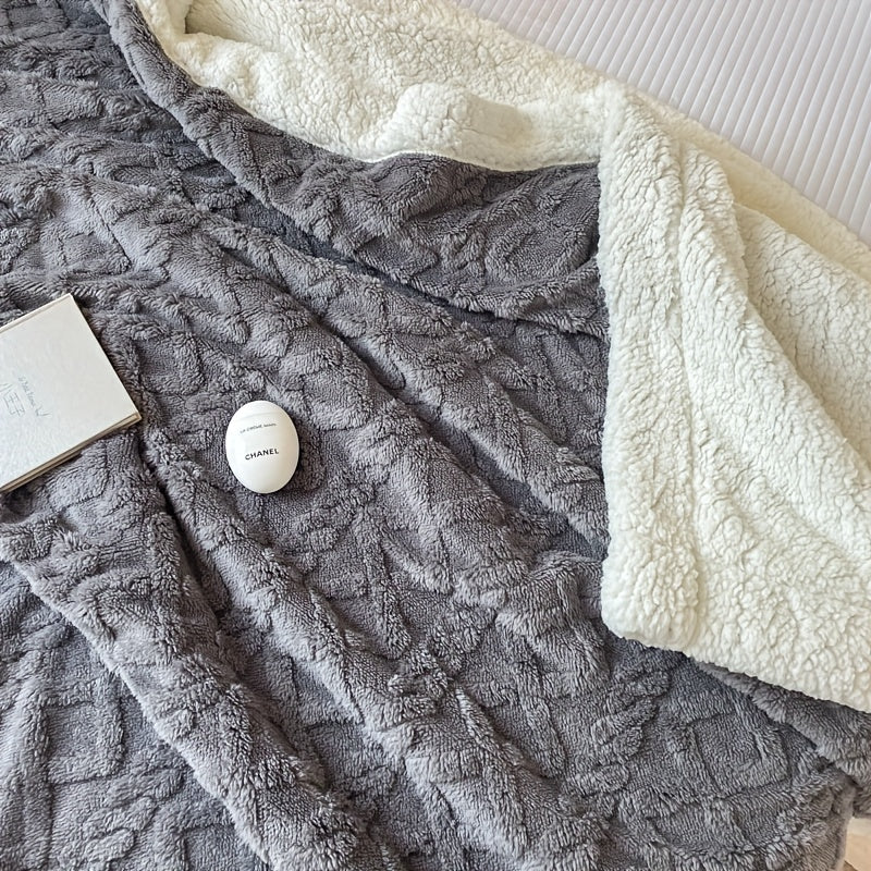 Couverture en polaire grise et blanche sur un lit, avec un livre et un œuf de bain Chanel. Literie confortable, accessoires de luxe, détente.