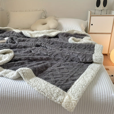 Couverture en laine grise et blanche sur un lit, chambre moderne et minimaliste, oreiller ergonomique, ambiance cosy et confortable.
