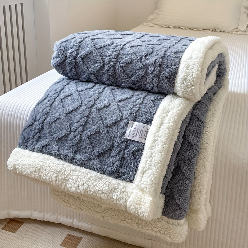 Couverture en laine grise et blanche, motif géométrique, posée sur un lit blanc. Idéale pour décoration intérieure et confort hivernal.