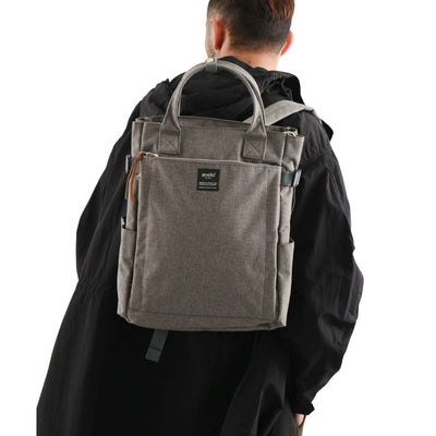 Sac à dos gris élégant porté par une personne, design moderne avec poignées, idéal pour le voyage et le quotidien. Accessoire mode tendance.