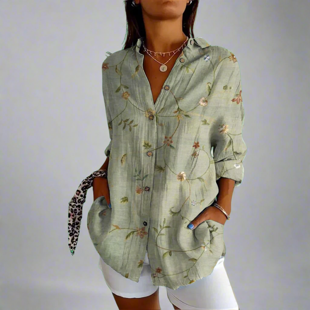 Chemisier vert à motifs floraux, manches longues, col ouvert, porté par une femme avec un short blanc. Style décontracté et élégant.