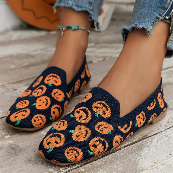 Chaussures en toile bleue avec motifs citrouille orange, portées avec un jean effiloché. Style automnal, mode décontractée, tendance Halloween.