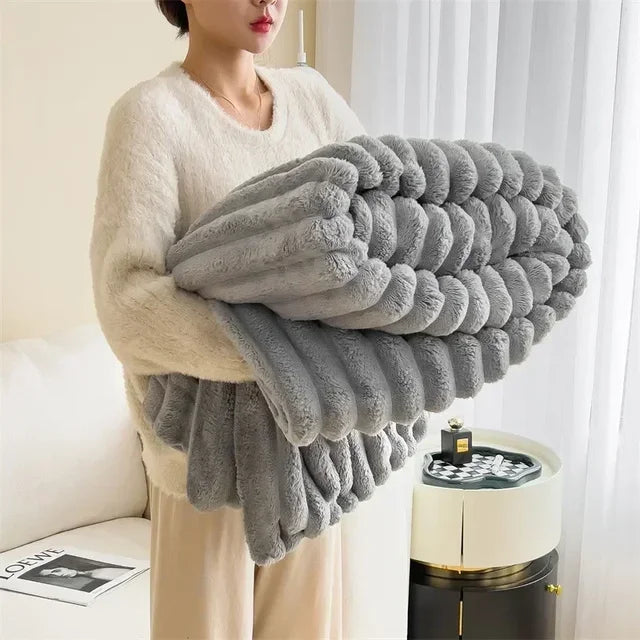 Femme tenant une couverture en fausse fourrure grise, douce et moelleuse, dans un salon moderne. Décoration intérieure, confort, textile maison.