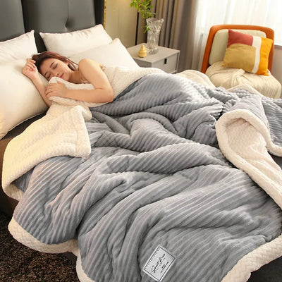 Femme dormant paisiblement sous une couverture en peluche grise et blanche dans une chambre moderne, lit confortable, ambiance cosy et relaxante.