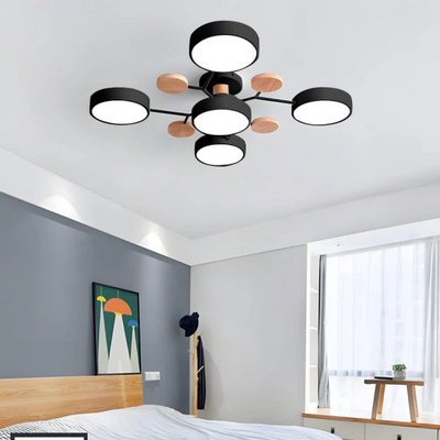 Plafonnier moderne noir et bois à cinq lumières LED, installé dans une chambre contemporaine avec mur gris et décoration minimaliste.