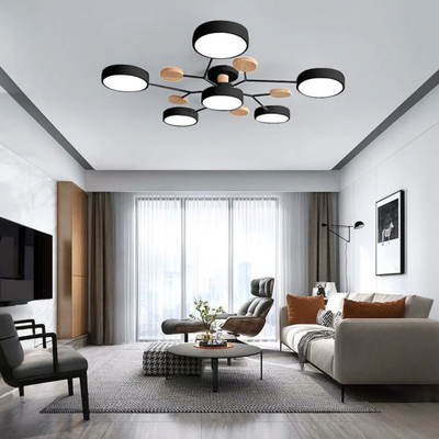 Plafonnier moderne noir et bois dans un salon élégant avec canapé blanc, table basse ronde, et grandes fenêtres. Éclairage design contemporain.