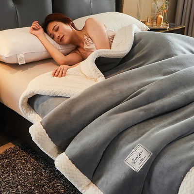 Femme dormant paisiblement sous une couverture en polaire grise et blanche sur un lit confortable, chambre moderne, ambiance cosy et relaxante.