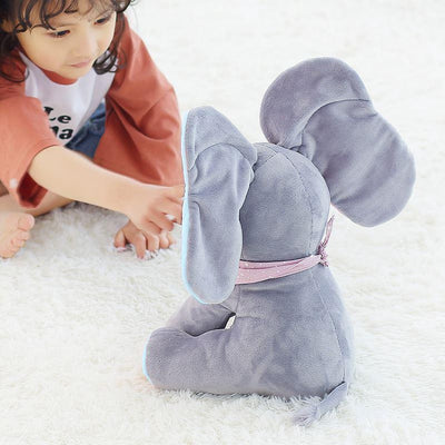 Enfant jouant avec un éléphant en peluche gris sur un tapis blanc, jouet doux et câlin, idéal pour chambre d'enfant, cadeau parfait pour bébé.