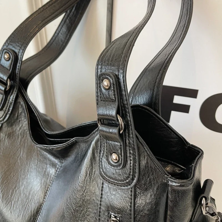 Sac à main en cuir noir élégant avec détails métalliques, anses robustes, design moderne. Accessoire mode chic pour femmes.