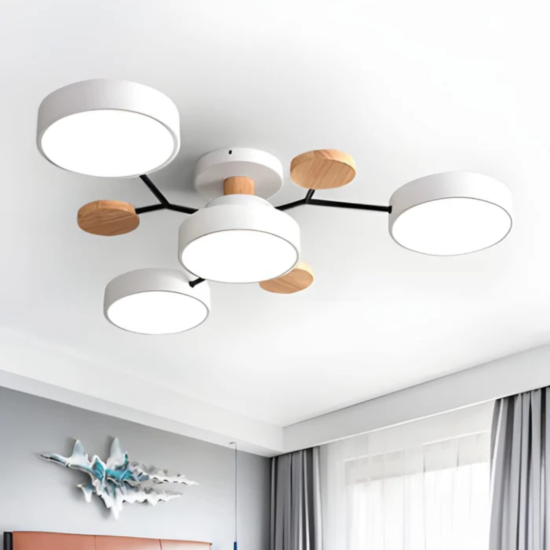 Plafonnier moderne à LED avec abat-jours circulaires blancs et détails en bois, installé dans un salon lumineux avec rideaux gris.