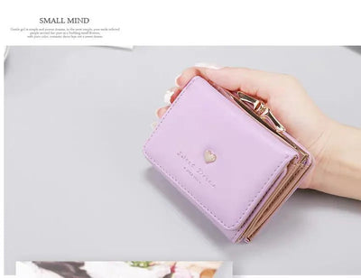 Portefeuille rose pastel en cuir, design compact, avec fermeture à bouton doré et motif cœur. Accessoire mode élégant pour femmes.