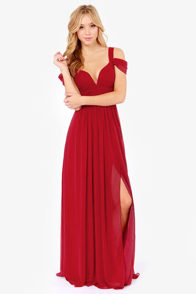 Robe longue rouge élégante avec épaules dénudées et fente, portée par une femme blonde. Mode soirée chic, tendance et glamour.