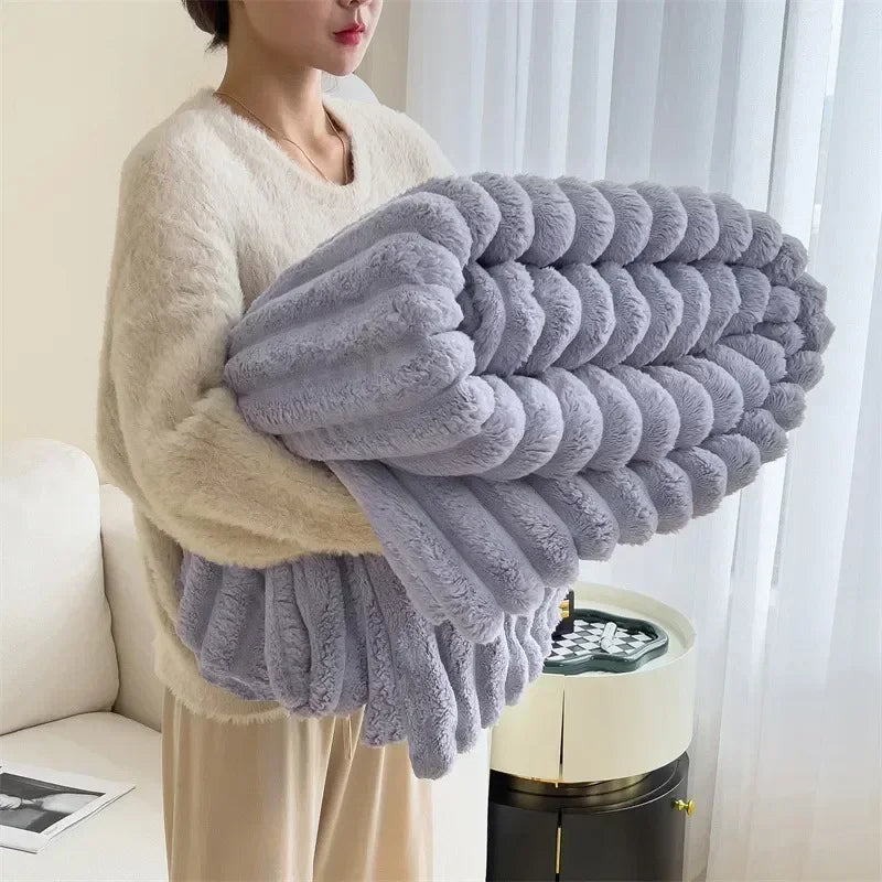 Femme tenant une couverture en peluche grise, douce et moelleuse, dans un salon moderne. Tissu confortable idéal pour l'hiver et la décoration intérieure.