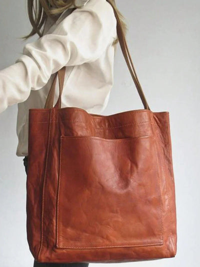 Sac cabas en cuir marron porté par une femme en chemise blanche, design élégant et spacieux, idéal pour le shopping ou le quotidien.