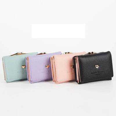 Quatre portefeuilles en cuir synthétique, couleurs pastel et noir, avec fermeture éclair dorée et motif cœur, sur fond blanc. Accessoires mode élégants.