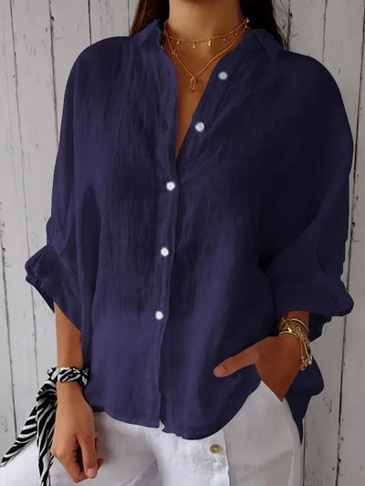 Chemise ample bleu marine pour femme, manches retroussées, boutons blancs, associée à un pantalon blanc. Style décontracté et élégant.
