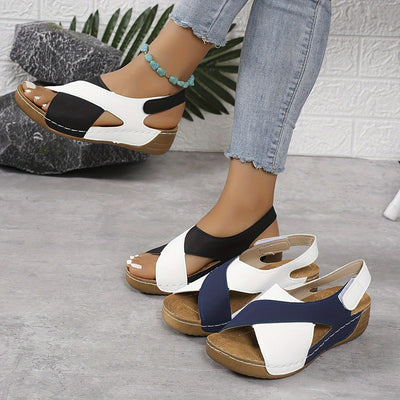 Sandales compensées bicolores en cuir noir et blanc, portées avec un jean décontracté. Chaussures d'été tendance pour femmes, confortables et élégantes.