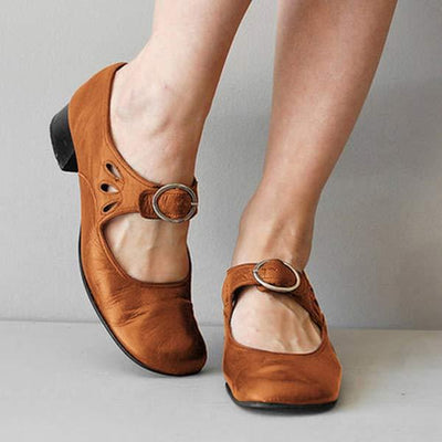 Chaussures Mary Jane en cuir marron avec boucle, talon bas noir, portées par une personne debout. Mode féminine, chaussures élégantes et confortables.
