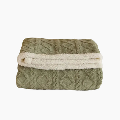 Couverture en laine polaire verte pliée, motif texturé, bordure blanche douce. Idéale pour salon, chambre, confort et décoration intérieure.