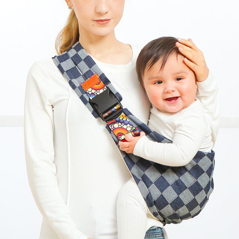 Femme portant un bébé souriant dans un porte-bébé à carreaux bleu et blanc, design ergonomique, confort et sécurité, accessoire parental pratique.