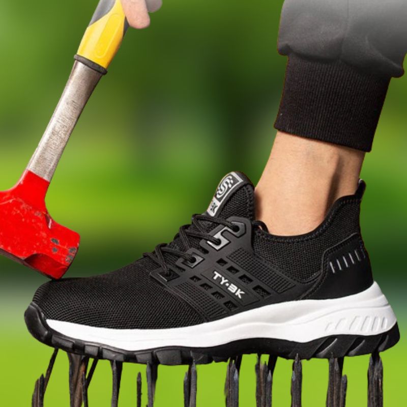 Chaussure de sport noire résistante avec semelle blanche, testée sous un marteau rouge, sur fond vert. Chaussure de sécurité, antidérapante, durable.