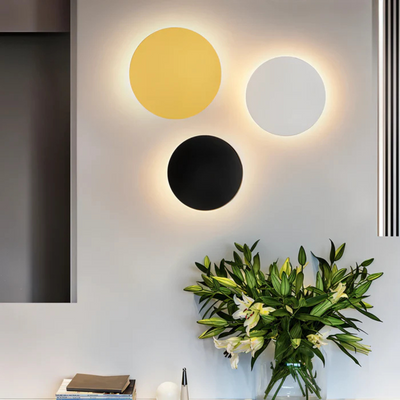 Applique murale moderne avec trois cercles lumineux jaune, blanc et noir, décor minimaliste, fleurs de lys blanches en vase, intérieur contemporain.