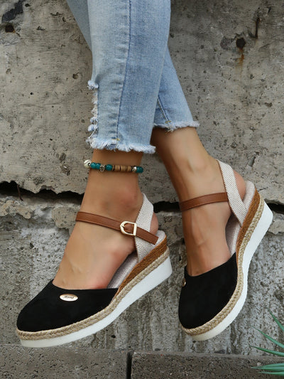 Sandales compensées noires en daim avec bride marron, portées avec un jean déchiré. Chaussures d'été tendance pour femmes, style décontracté.