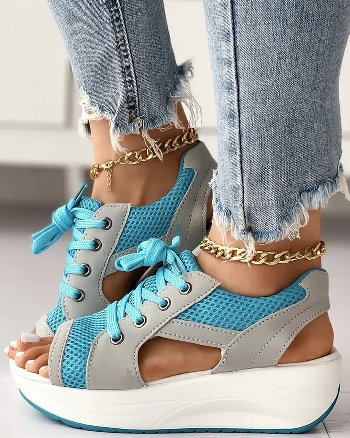 Chaussures compensées ouvertes en maille bleue et grise, lacets assortis, portées avec un jean effiloché et bracelets chaîne dorés.