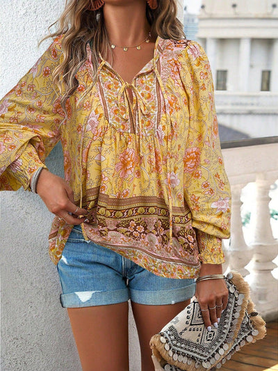 Femme en blouse bohème jaune à motifs floraux, short en jean, tenant une pochette ethnique. Mode estivale, style décontracté chic.
