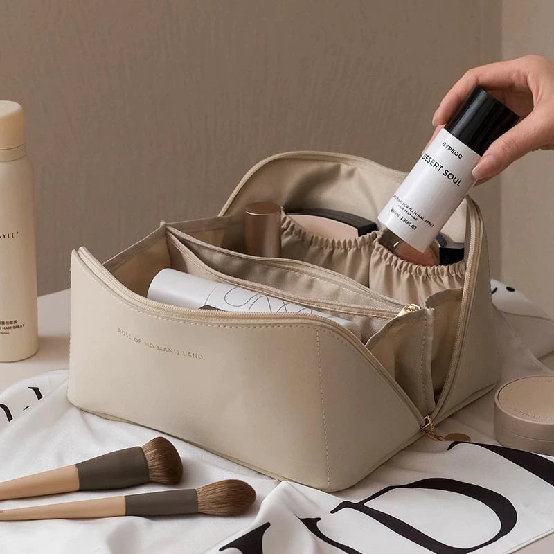 Trousse de maquillage beige ouverte avec produits cosmétiques, pinceaux et flacon de spray. Accessoire beauté pratique pour organisation maquillage.