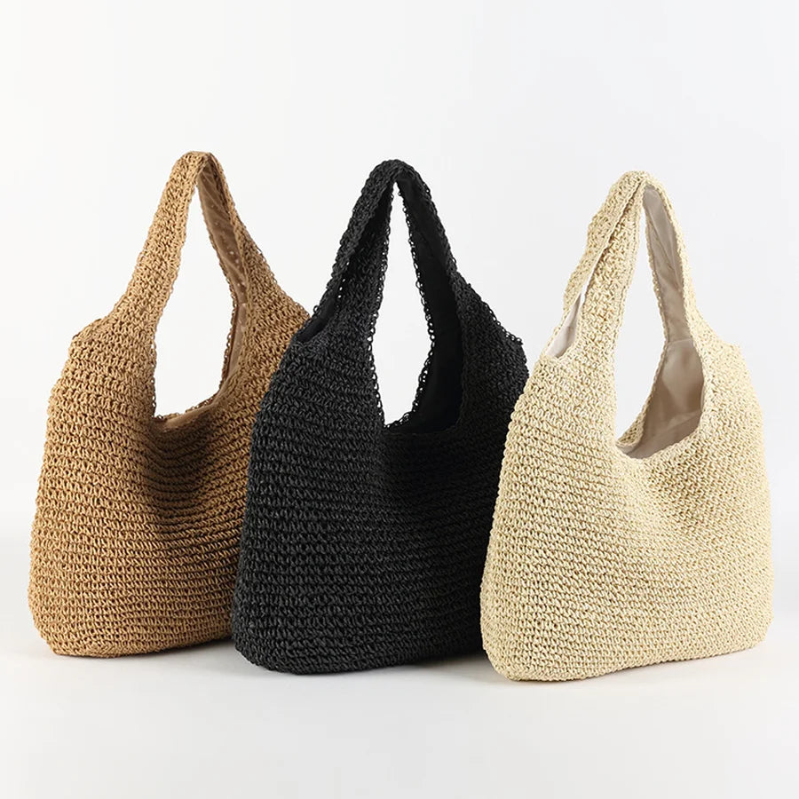 Trois sacs à main en paille tressée, couleurs beige, noir et marron, posés sur fond blanc. Accessoires mode été, style bohème chic.