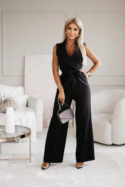 Femme élégante en combinaison noire, tenant un sac à main de luxe, posant dans un salon moderne. Mode féminine chic, style contemporain.