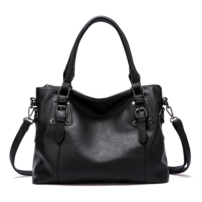 Sac à main en cuir noir élégant avec bandoulière amovible, boucles décoratives et poignées doubles. Accessoire mode femme chic et tendance.