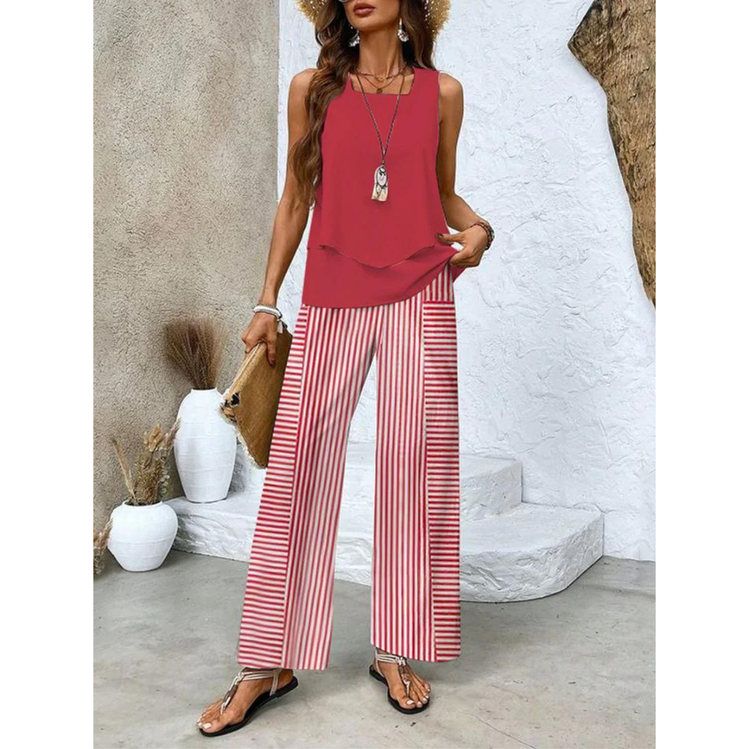 Femme en tenue estivale chic, portant un haut rouge et un pantalon rayé rouge et blanc, accessoirisée d'un chapeau de paille et d'un sac en osier.
