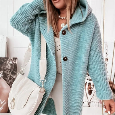 Femme portant un manteau en tricot bleu avec capuche, sac à main blanc, chemise à pois. Mode automne-hiver, style décontracté chic.