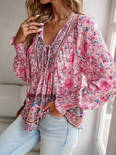 Blouse bohème rose à motifs floraux, manches longues, portée par une femme. Style décontracté, tendance mode féminine, idéal pour printemps-été.