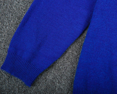 Manche de pull bleu en laine sur fond de tapis gris, texture douce et chaude, vêtement d'hiver élégant, mode confortable.